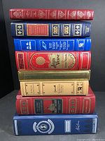 Stack of eight hardcover books with visible titles and colorful, classic bindings.