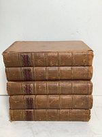 Stack of five leather-bound volumes of Plutarch's Lives showing spine wear and red spine labels.