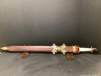 Full view of the replica sword encased in a wood and metal scabbard, showing decorative brass fittings and the sword handle.