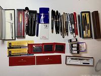 Overview image showing entire lot of modern fountain pens, boxed sets, and ink cartridges.
