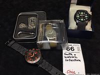Lot contents showing three military-style wristwatches and one pendant commando watch with tin case and accessories.