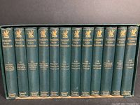 Photo of the spines of the 12 volumes showing the titles and the publisher's name embossed in gold on a green cloth binding.