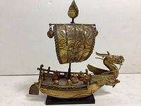 Front and side perspective of vintage celluloid model dragon head junk boat showing detailed dragon sail and seven lucky gods figurines on deck.