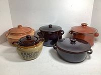 Front view of five ceramic crocks with lids, showing variety of glaze colors and shapes. Boston Bean Pot marked on one smaller crock.