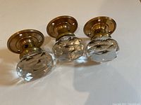 Three crystal door knobs positioned side-by-side, showing the clear faceted glass knobs and brass fittings.