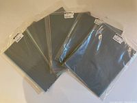 Six sealed packs of 3M wet or dry polishing paper displayed overlapping on a flat surface.