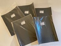 Five sealed black sandpaper packs labeled by Gesswein, wrapped in plastic, showing different grit sizes.