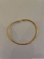Full view of circular gold bangle laid flat