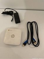 HP mini computer with Chrome logo, power adapter, and HDMI cable displayed on white surface