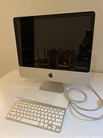 Apple iMac 20-inch desktop with two keyboards on white surface.