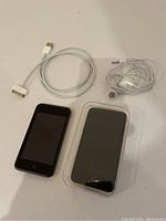 Two iPods and accessories on white background including earbuds, charging cable and protective case on iPod Touch.