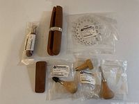 Top view of all jewelry making tools, including ring clamp, bezel roller, dapping block discs, awl, and other wooden hand tools, all brand new in original packaging.