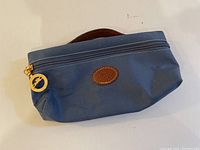Front view of blue Longchamp 1948 pouch showing leather logo patch and zipper.