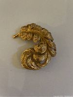 Gold plated Monet feather brooch showing detailed feather design and texture