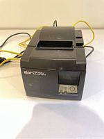 Front-side view of black Star TSP100 FuturePRNT receipt printer showing control panel and label logo with cables in background.