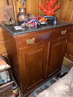 Full view of the wood cabinet with various items on the stone top