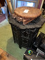 Two carved wood tables stacked, showing overall size and shape with dark wood table on bottom and lighter table on top