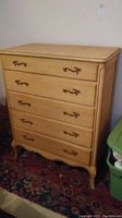 Full view of the wooden chest with 5 drawers showing hardware and legs.