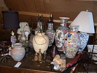 Wide view of attic collection showing various pottery and glass lamps, colorful vases, small bottles, figurines, and lamp shades