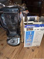 Blender and boxed juice extractor on wooden floor showing both items in lot