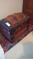 Full view of the wooden dome top trunk chest showing wooden slats and curved top with black metal reinforcements.