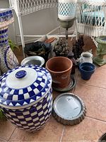 Full lot showing multiple pots and planters including large blue and white ceramic jar, clay pots, metal saucers, green pedestal vase, rabbit figurines, and metal lantern.