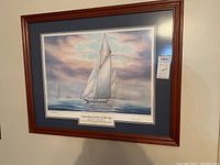 Framed art print depicting sailboats racing on water under a partly cloudy sky, wood frame with double matting in blue and beige.