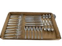 Full set of 32 cutlery pieces laid out in a cardboard box showing 12 forks, 8 butter knives, 6 teaspoons, and 6 soup spoons.