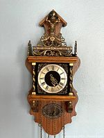 Front view showing wooden case, brass columns, dial and pendulum