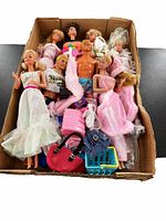 Lot of assorted vintage Barbie and Ken dolls with accessories shown in a cardboard box.