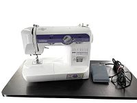 Front side view of white Brother XL5500 sewing machine with attached foot pedal on a black surface.