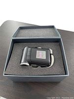 Digital camcorder in protective foam inside a box, showing the main body of the camera, compact and black with a wrist strap.