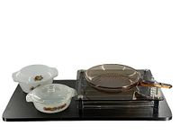 Photo showing the entire lot including two milk glass covered casseroles, amber glass frying pan, and black coffee pod holder on a dark surface.