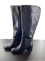 Side profile view of the right boot showing full tall height, side zipper, block heel, and smooth black finish.