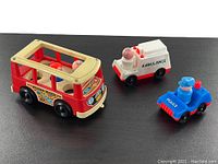 Lot of 3 vintage Fisher Price mini vehicles: red Mini Bus, white Hospital Ambulance with doctor figure, blue Police Car with policeman figure, shown together on black background.