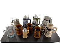 Lot of nine beer steins assorted styles and brands on black surface