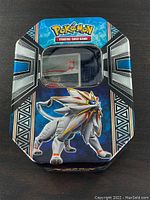 Front view of a rectangular Pokemon TCG tin featuring Solgaleo artwork with window lid.