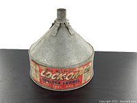 Front angle view of the galvanized steel tractor funnel showing conical shape and original label with red and black text on beige background.