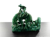 Front view of the vintage green ceramic planter depicting a horse with rider surrounded by cactus design.