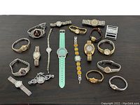 Overview of 19 vintage watches laid out on a surface, showing various band styles and dial designs.