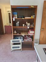 Full shelf view of lot items including step stool, books, photo frames, and small household items