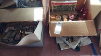 Box of mixed assorted candles and candle holders, various types and colors, in open boxes and plastic wrap.