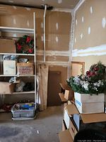 Photo showing shelving with boxed Christmas decorations including wreaths, faux greenery, and boxes of ornaments and bows.