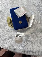Full lot displayed in a clear bowl containing commemorative coins, certificates of authenticity, and a blue display box on a lace tablecloth.
