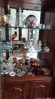 Wide view of shelf with assorted carafes, figurines, glass items, and copper bowls
