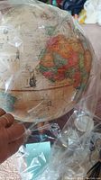 Close-up view of the vintage style globe showing Africa with artistic embellishments and country labels, protected in plastic.