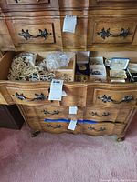 Drawer open showing strands of faux pearl necklaces and small boxes with brooches and earrings inside.