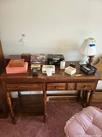 Wide shot of all jewelry boxes on wooden table including different sizes and styles, alabaster box, lamp in background