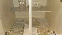 Glass baking pans and dishes of various shapes and sizes arranged on shelving.