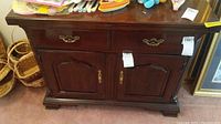 Front view of Thomasville serving bar showing two drawers with brass handles and double cabinet doors below with decorative lock.